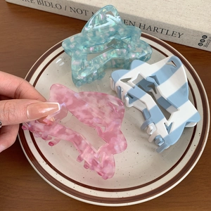 Star-shaped acetate hair claws in glittery teal, pink marble, and blue stripes