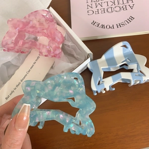 Three acetate hair claws with marble and iridescent designs for hair styling