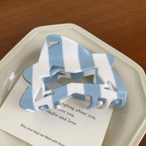 Detail of blue and white striped acetate hair claw clip with star hollow design