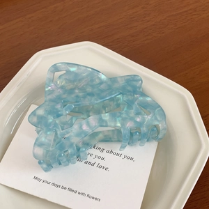 Close-up of light blue acetate hair claw with iridescent shell texture and wave design