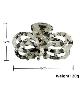 Detail showing an 8x5cm hollow butterfly claw clip with black and white floral pattern