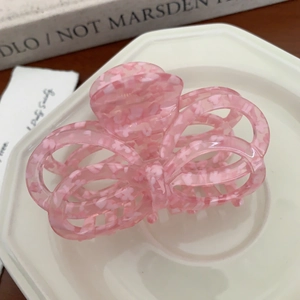 Detail view of pink floral acetate butterfly hair claw clip in an elegant ceramic tray