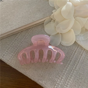 Macro di una pinza per capelli rosa ciliegio con struttura in resina liscia e traslucida