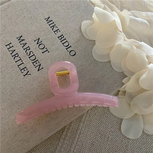 Dettaglio di un fermaglio per capelli in marmo rosa su un libro con petali di seta