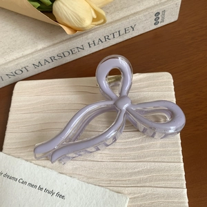 Detail of a purple bow hair claw clip with clear resin finish and gold spring mechanism