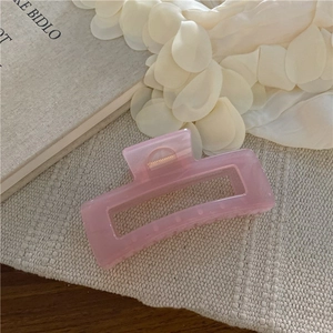 Dettaglio di una grande pinza per capelli rettangolare rosa con trama marmorea