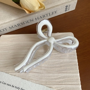 Detailed view of a white bow hair claw clip with a transparent acrylic finish