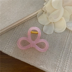Dettaglio ravvicinato di un fermaglio per capelli rosa a fiocco con molla in metallo oro