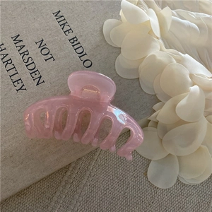 Dettaglio macro di un fermaglio per capelli in resina rosa su petali di seta
