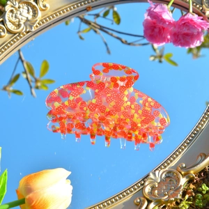 Haarklammer aus Acryl mit Erdbeermuster und Spiegelreflexion vor blauem Himmel