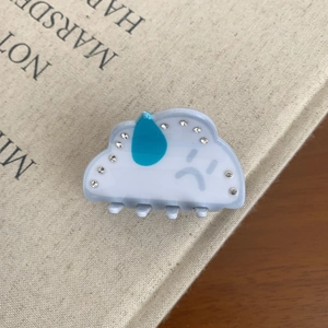 Détail d'une pince à cheveux en acrylique en forme de nuage avec des strass bleus brillants