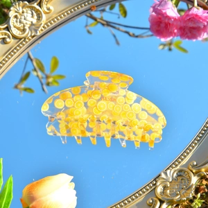 Detail der gelben Acryl Haarklammer mit Zitronenmuster und Gravur auf einer Spiegelfläche