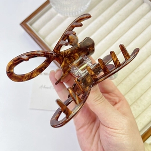 Macro detail of tortoiseshell acetate hair claw clip with golden spring mechanism