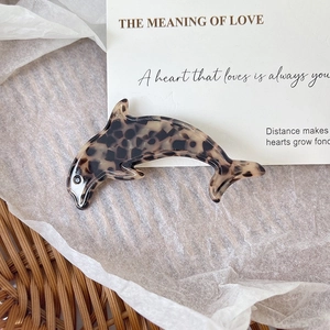 Macro shot of dolphin-shaped hair clip with elegant tortoiseshell patterns and glossy finish
