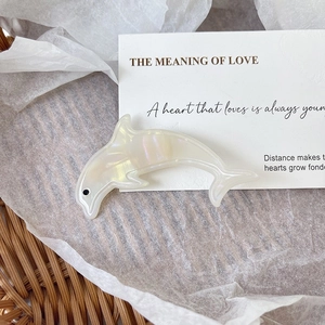 Detailed view of a pearlescent dolphin hair clip made of premium acetate in a lifestyle set