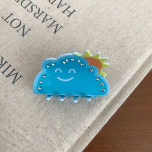 Détail de la pince à cheveux nuage bleu avec visage souriant et strass brillants