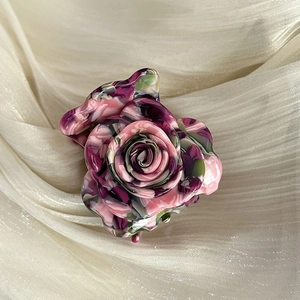 Close-up of artistic marble textured rose hair claw clip with floral pattern detail