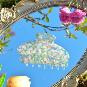 Detailansicht der großen Acryl-Haarklammer mit Blumendruck auf einer Spiegelfläche