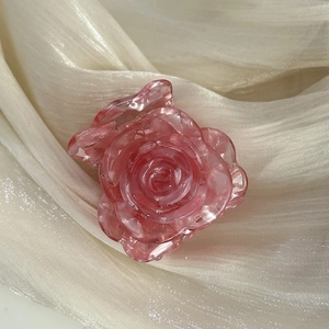 Macro shot of pink marble texture acetate rose flower hair claw clip on silk fabric