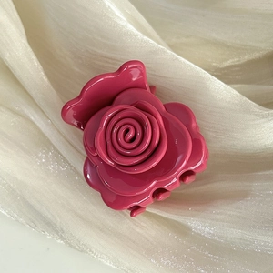 Macro shot of 3D rose hair claw clip in deep pink finish on romantic tulle fabric
