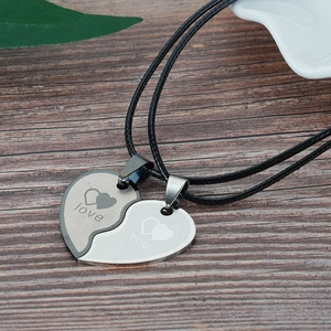 Detail of heart puzzle couple necklaces with love and you engraving on wooden background