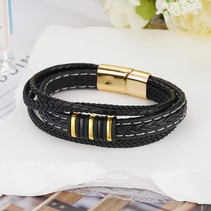 Macro detail of men's multilayer braided black leather bracelet with gold magnetic clasp