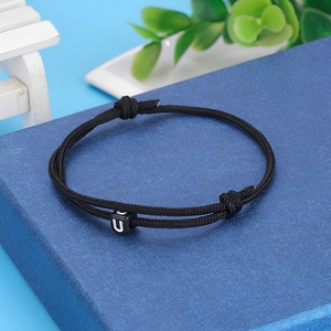Close-up of black braided cord bracelet with white letter U bead and adjustable knots