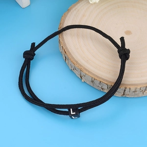 Minimalist handmade woven wax cord bracelet with white letter L charm on blue background
