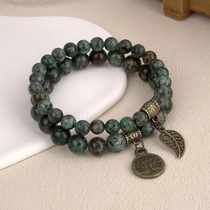 Détail des breloques Arbre de Vie et feuille sur bracelet multicouche en pierres vertes