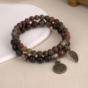 Détail de bracelets en perles avec breloques arbre de vie et feuille en bronze