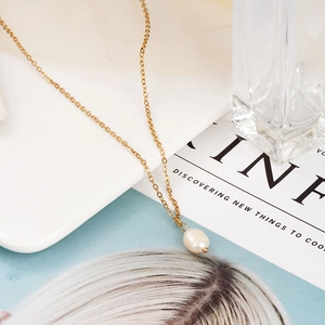 Minimalistische 18K Goldkette mit Süßwasserperlenanhänger auf einer Zeitschrift