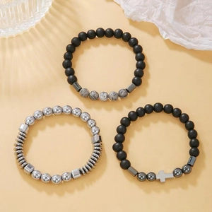Detail of three-piece men's beaded bracelet set featuring black matte beads and silver cross