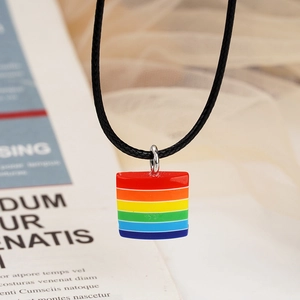 Detail of a rainbow rectangle charm necklace with a black cord on decorative background