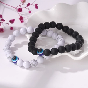 Gros plan de bracelets en perles turquoises noires et blanches avec breloque œil bleu