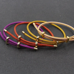 Détail de bracelets tressés réglables colorés avec des accessoires en métal doré poli