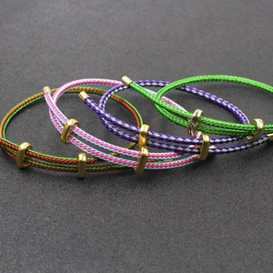Gros plan de bracelets en fil d'acier tressé multicolore avec boucles dorées réglables