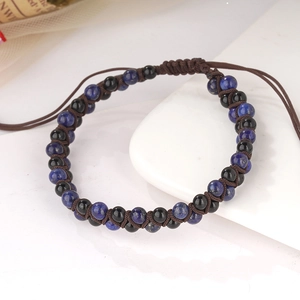 Dettaglio di un bracciale intrecciato a mano con perle blu scuro e cordino marrone regolabile