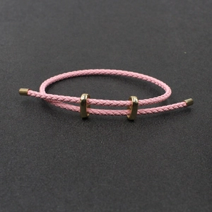 Détail d'un bracelet en corde tressée rose avec structure ajustable et anneaux en métal doré