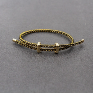 Détail du bracelet tressé noir et or avec boucles coulissantes métalliques réglables