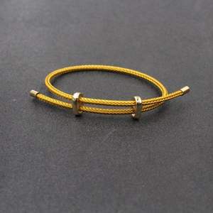Détail d'un bracelet doré réglable avec texture tissée et boucles coulissantes en métal