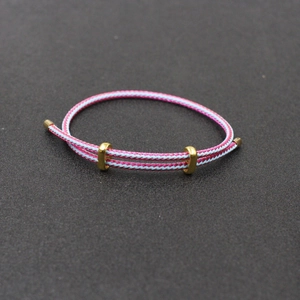Détail du bracelet tressé rose et bleu clair avec curseurs de réglage en métal doré