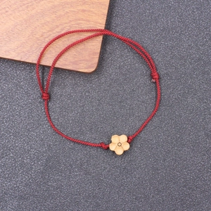 Handmade red braided cord bracelet featuring a carved peach wood plum blossom flower charm