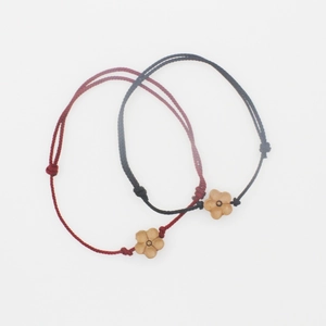 Detail of red and black hand-woven bracelets with carved wooden plum blossom charms