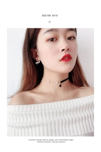 Detail of choker necklace with black heart pendant, velvet ribbon, pearls, and cherry earrings