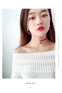Detail view of a red velvet and gold chain choker with pearls and a heart pendant