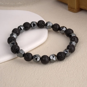 Close-up of porous black lava stone and faceted hematite beads on a minimalist bracelet