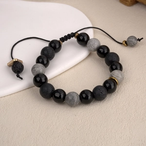 Dettaglio del bracciale regolabile in pietra lavica nera con perle marmorizzate e cordino