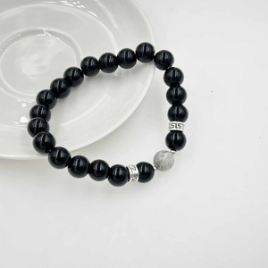 Dettaglio macro del bracciale con perline nere, pietra marmorea e distanziatori in argento