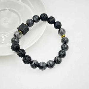 Dettaglio macro di perle in pietra lavica nera e marmo grigio su un bracciale minimalista