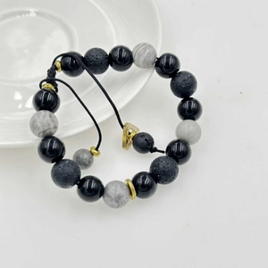 Dettaglio di perle in pietra lavica e marmo su un bracciale a cordoncino regolabile